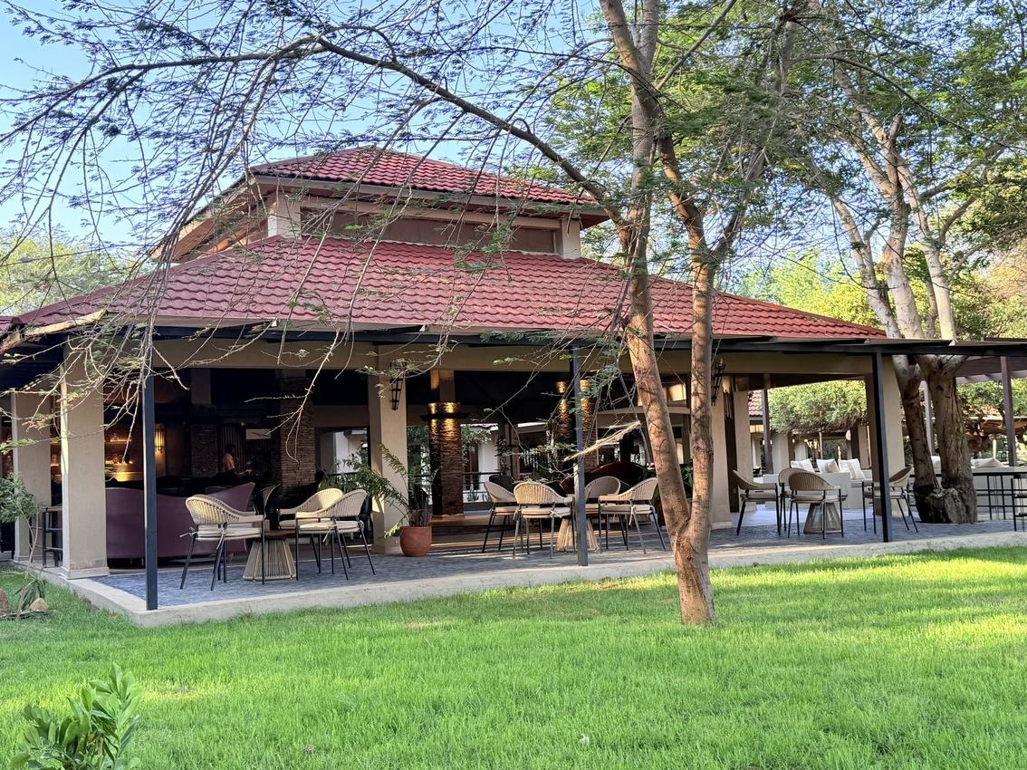 Lodge building with a red tiled roof and shaded terrace at Ashnil Aruba Lodge in Tsavo
