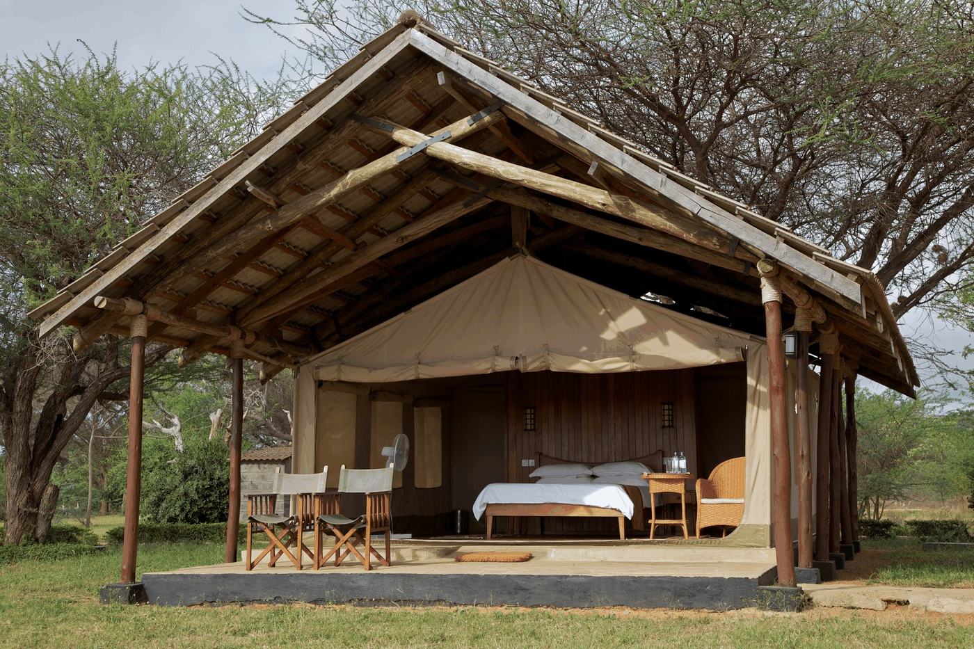 Canvas tent with a peaked thatch roof and chairs on its veranda at Ashnil Aruba Lodge