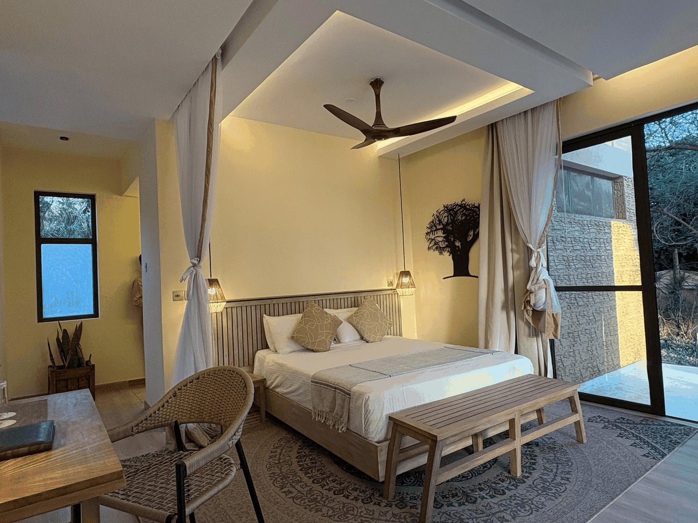 Modern bedroom with a canopy bed, ceiling fan and sliding glass doors at Ashnil Aruba Lodge