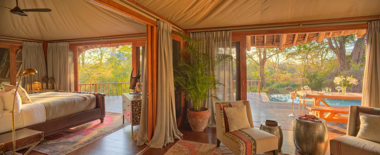 A tented suite at Finch Hattons, with the bed, a sitting area and the deck beyond.