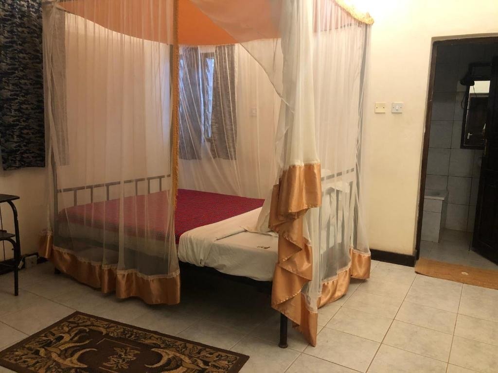 A canopy bed with gold trim sits beside the ensuite at Impala Safari Lodge