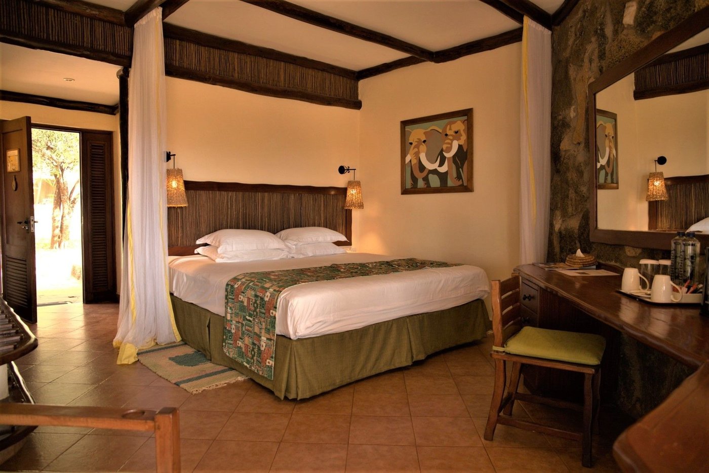 Cosy room with a wooden desk and chair beside the bed at Kilaguni Serena Safari Lodge