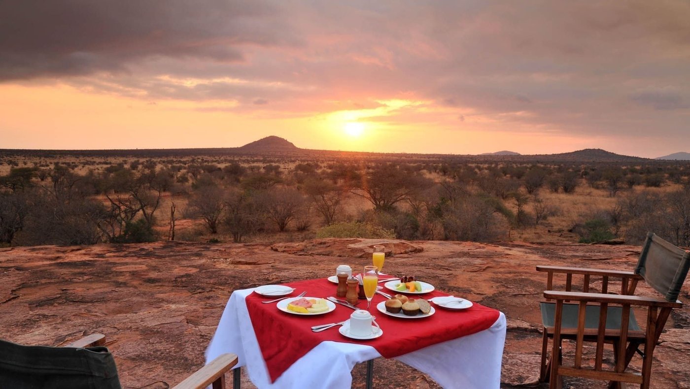 Breakfast table with a red cloth set on a rocky outcrop at Kilaguni Serena Safari Lodge