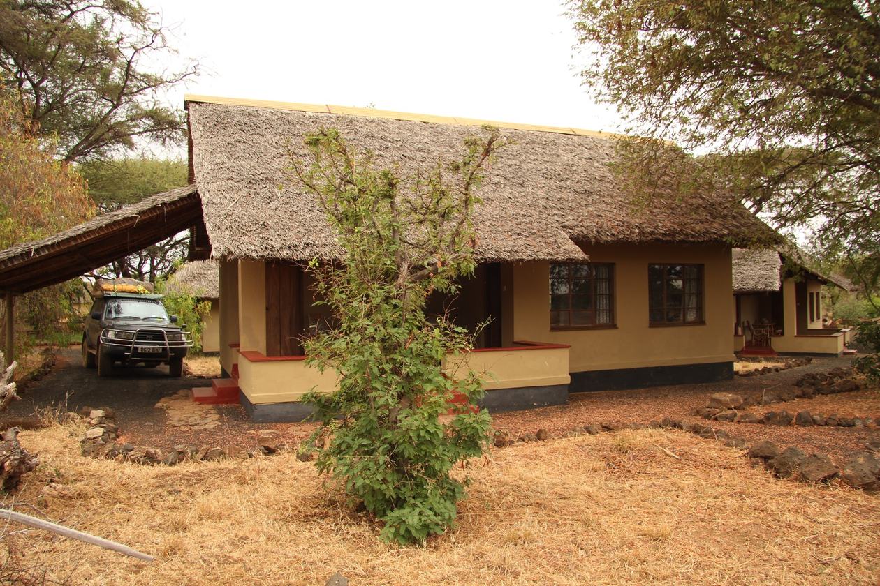 Thatched self-catering banda with a vehicle parked outside at Kitani Bandas in Tsavo