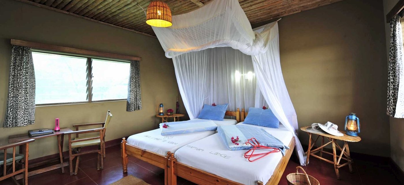 Twin beds under a mosquito net in a cottage at Kitani Bandas