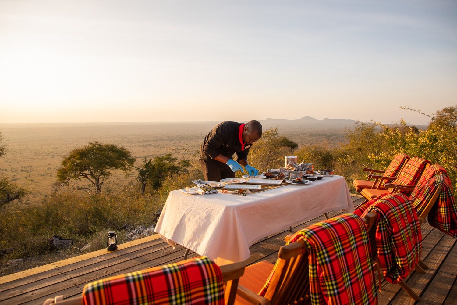 Breakfast being laid out on the deck, looking over the plains