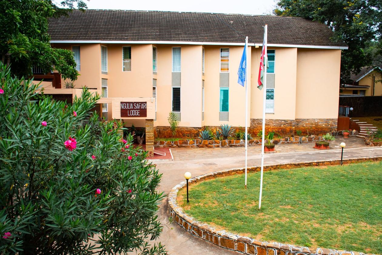 Flowering oleander fronts the cream building and sign at Ngulia Safari Lodge