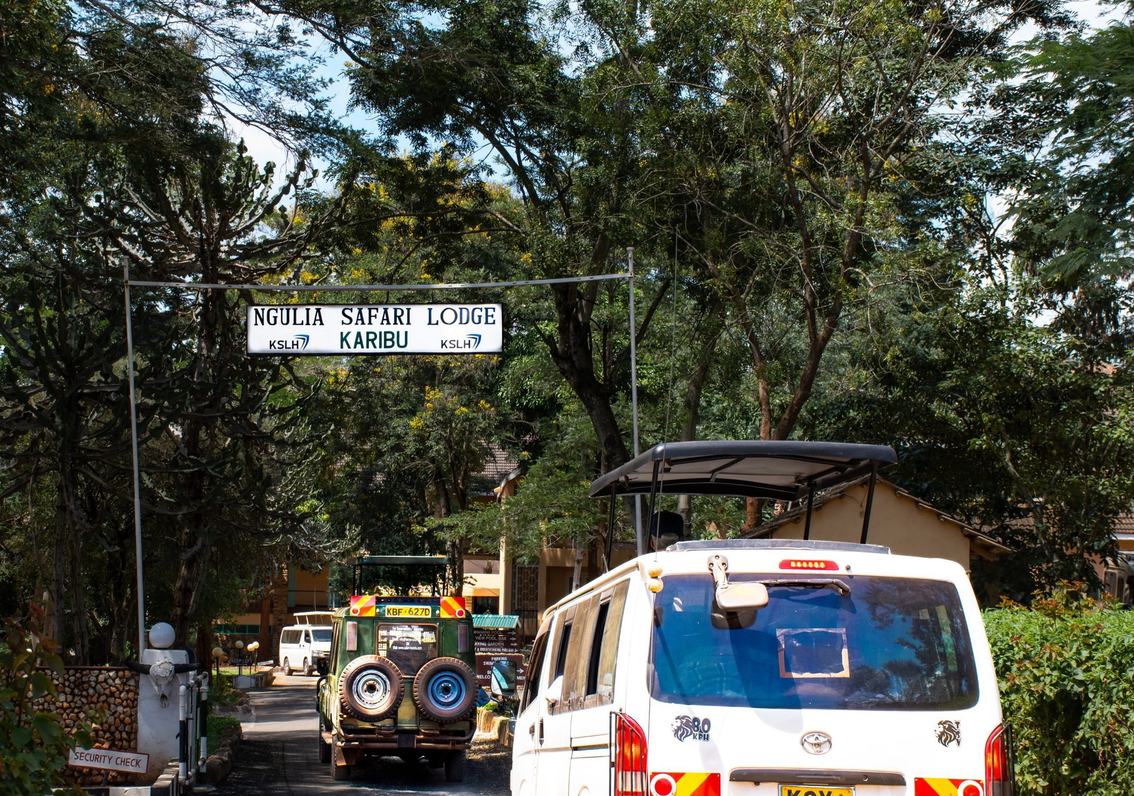 Safari vehicles pass beneath the entrance sign at Ngulia Safari Lodge
