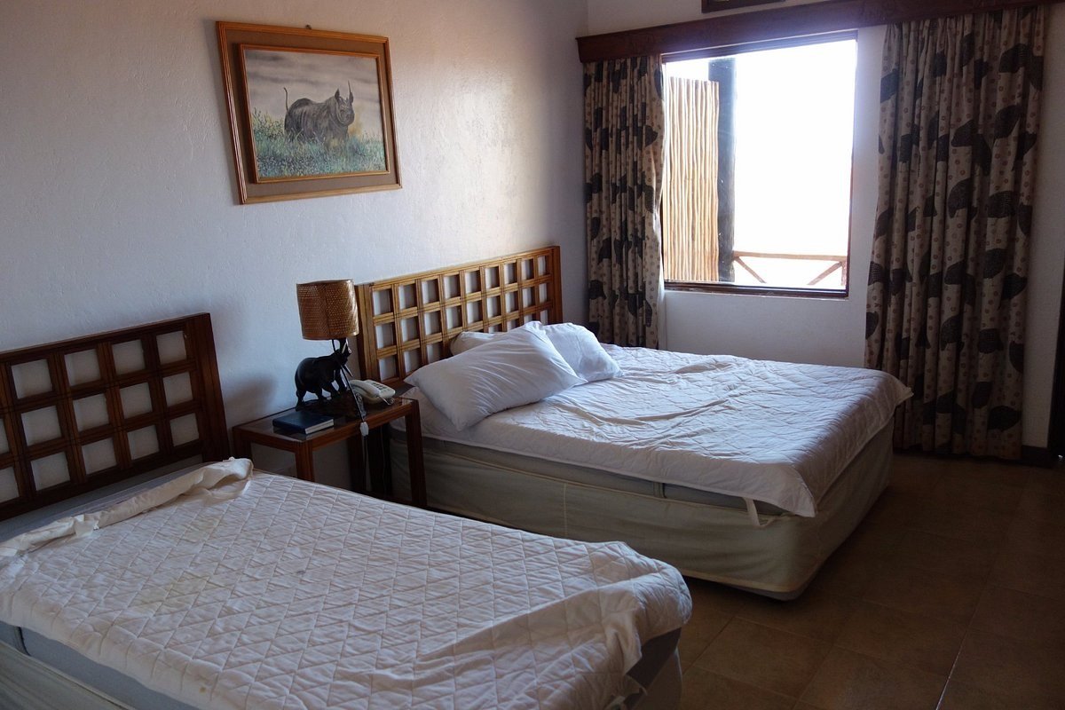 Twin beds with a wildlife print above the headboard in a room at Ngutuni Safari Lodge