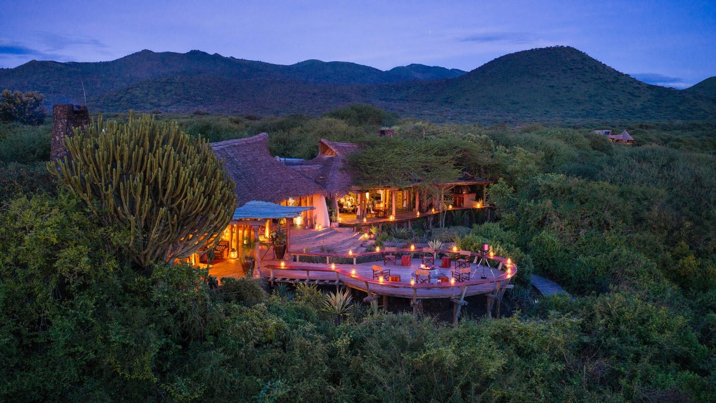 Thatched suites of ol Donyo Lodge glowing at dusk in the green Chyulu Hills near Tsavo