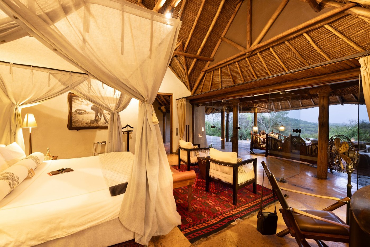 Canopied bed and lounge chairs in a suite overlooking the plains at ol Donyo Lodge