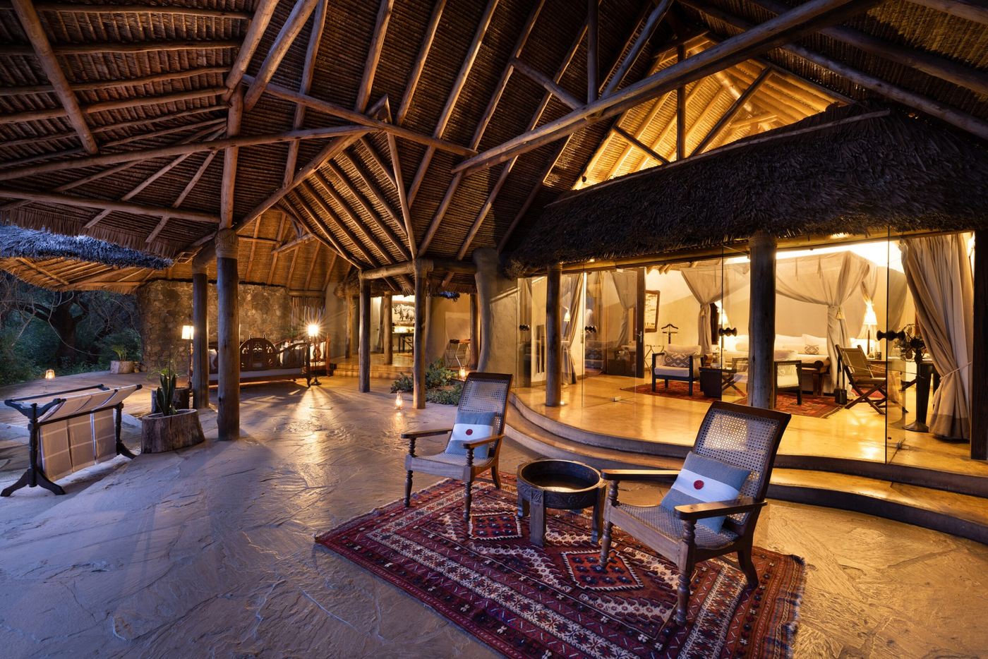 Open-sided thatched lounge with wooden beams and safari chairs at ol Donyo Lodge