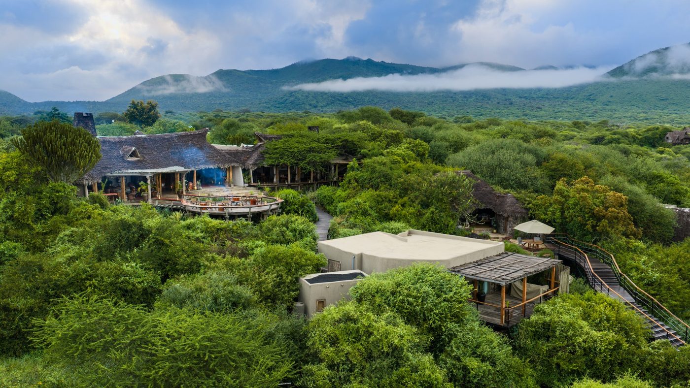 Aerial view of ol Donyo Lodge's thatched suites set among green hillside bush