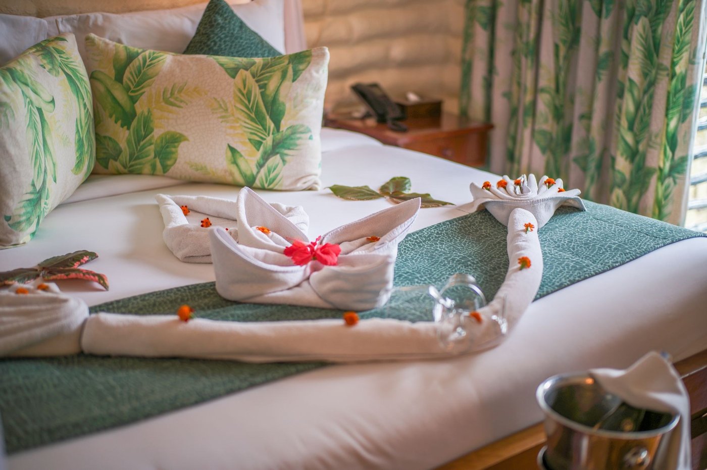 Bed with leaf-print cushions and swan towels at Taita Hills Safari Resort & Spa
