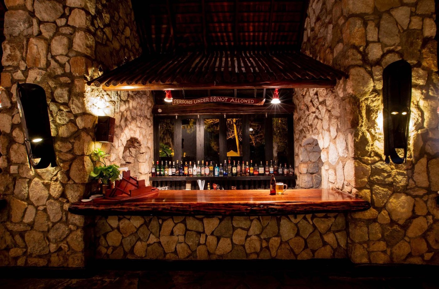 Bar lit warmly with bottles along the stone counter at Taita Hills Safari Resort & Spa