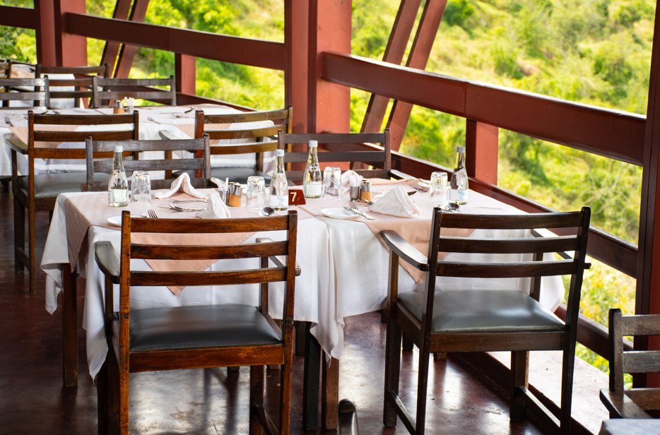 A dining deck with red steel trusses opens onto green hills at Voi Safari Lodge
