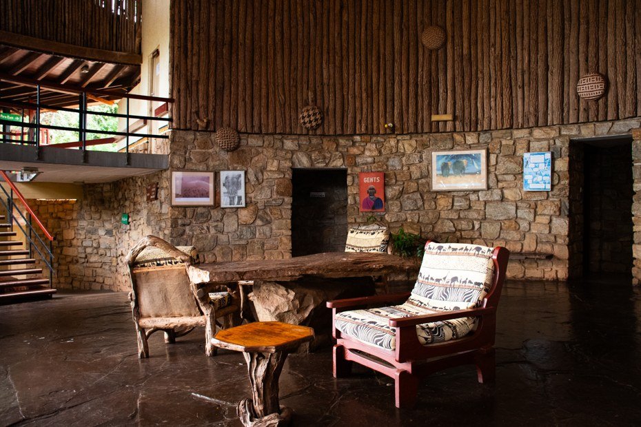 A stone-walled lounge with carved chairs and local art at Voi Safari Lodge