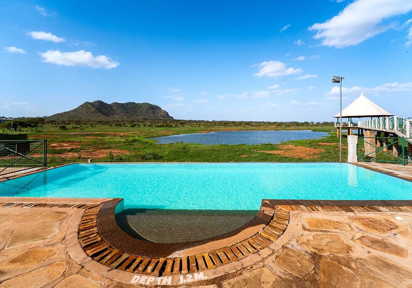 Curved infinity pool with a hill rising behind it at Voi Wildlife Lodge