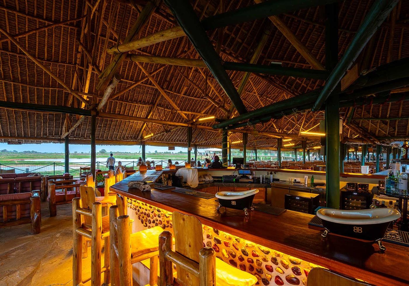 Thatched bar and lounge overlooking the dam through the boundary fence at Voi Wildlife Lodge