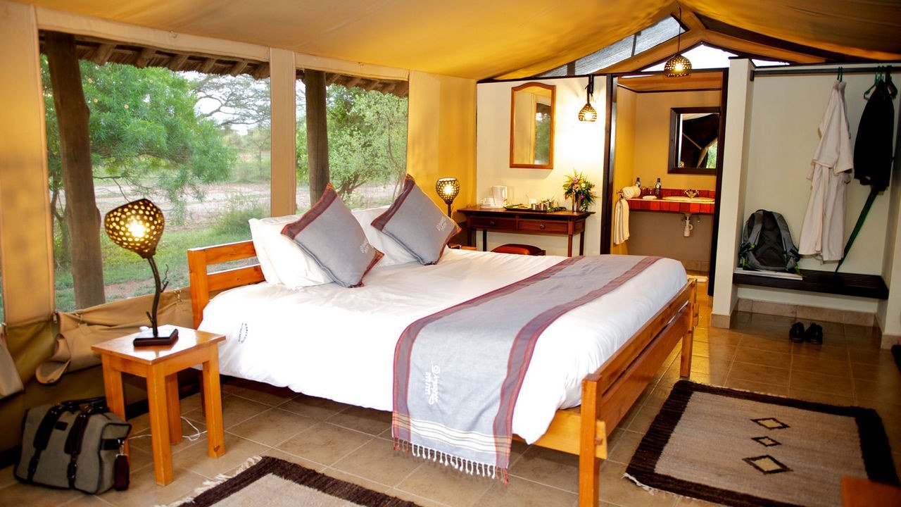 A tented bedroom opens to a dressing area and ensuite at Voyager Ziwani